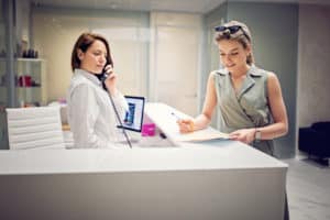women signing in at the front desk for her cosmetic procedure
