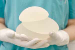 Woman holds breast implant options when preparing for breast augmentation.