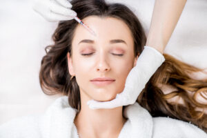Injector holds patient's head gently as she receives Botox between her eyebrows.